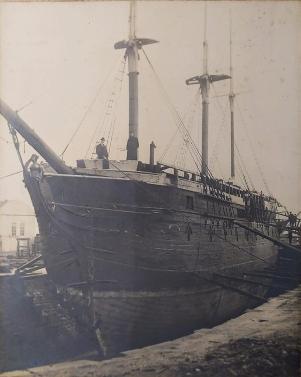 photo of a sailing ship undergoing work in dry dock, supported by wooden props.